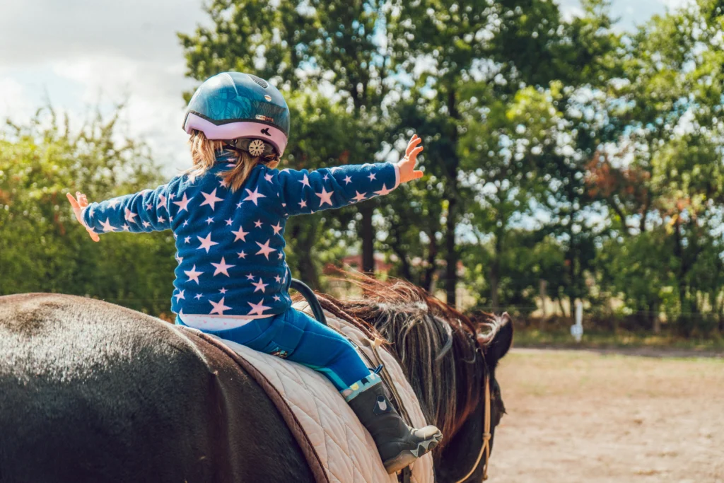 A young girl learning horseback riding with an instructor.