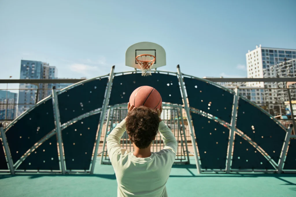 A group of children playing basketball on an outdoor court, demonstrating teamwork and excitement.