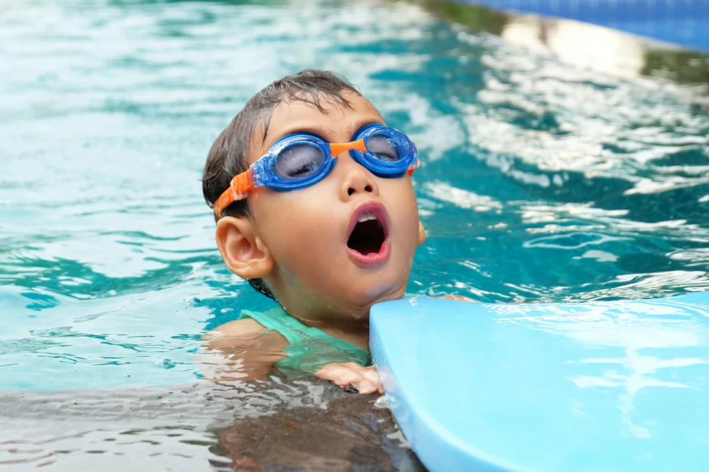 A young child learning to swim in a pool with a supportive instructor, focusing on safety and building confidence in the water.