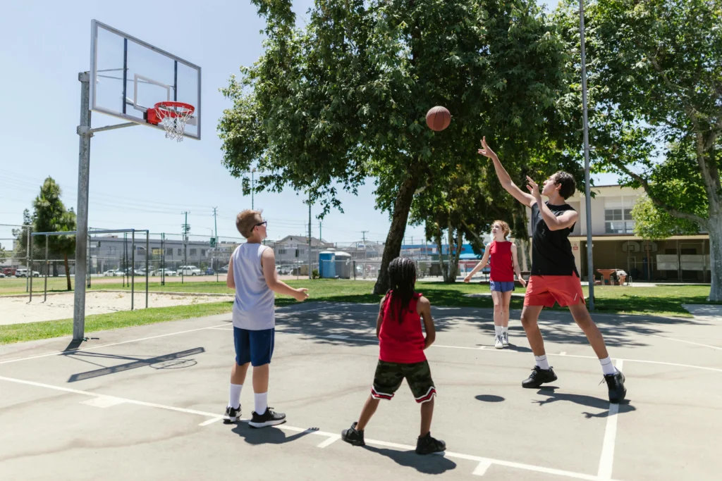 A group of children playing basketball on an outdoor court, demonstrating teamwork and excitement.